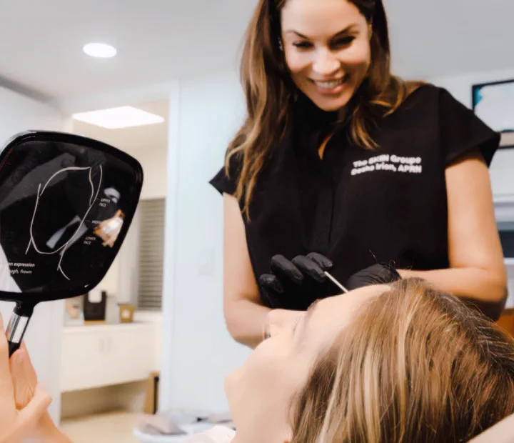 Desha Irion, APRN, reviewing facial treatment results with a client using a hand mirror